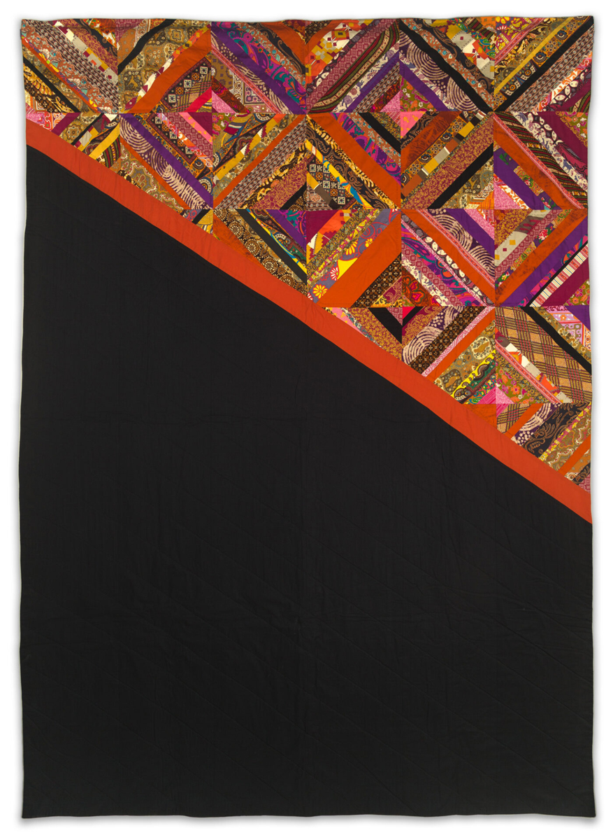 A quilt with a diagonal design: the top left half features intricate, colorful patchwork squares, while the lower right half is solid black, separated by a thin red stripe.