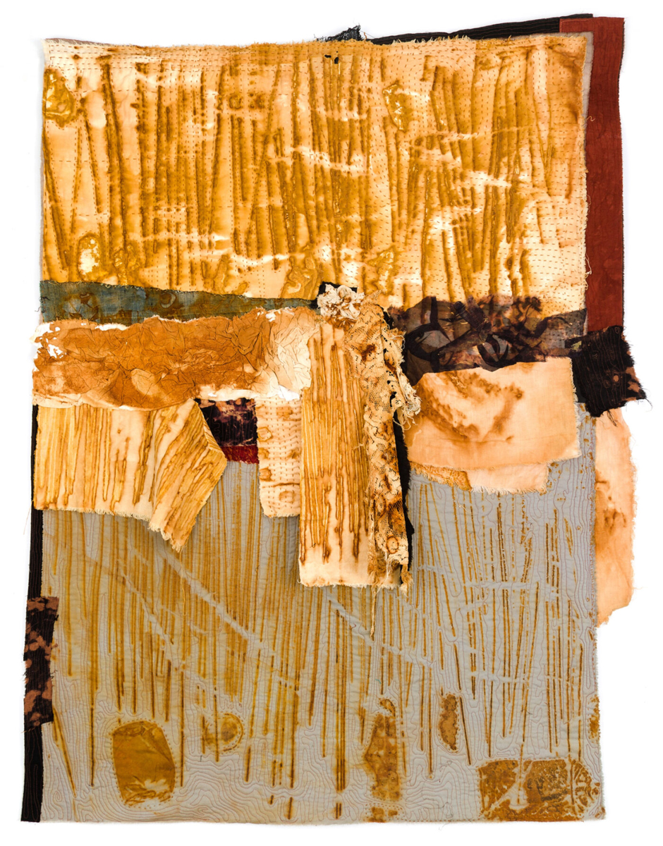 A textured abstract textile artwork with layered fabrics in earthy tones of gold, beige, brown, and touches of green. Vertical stitched and painted lines run across the surface, creating a sense of depth and movement.